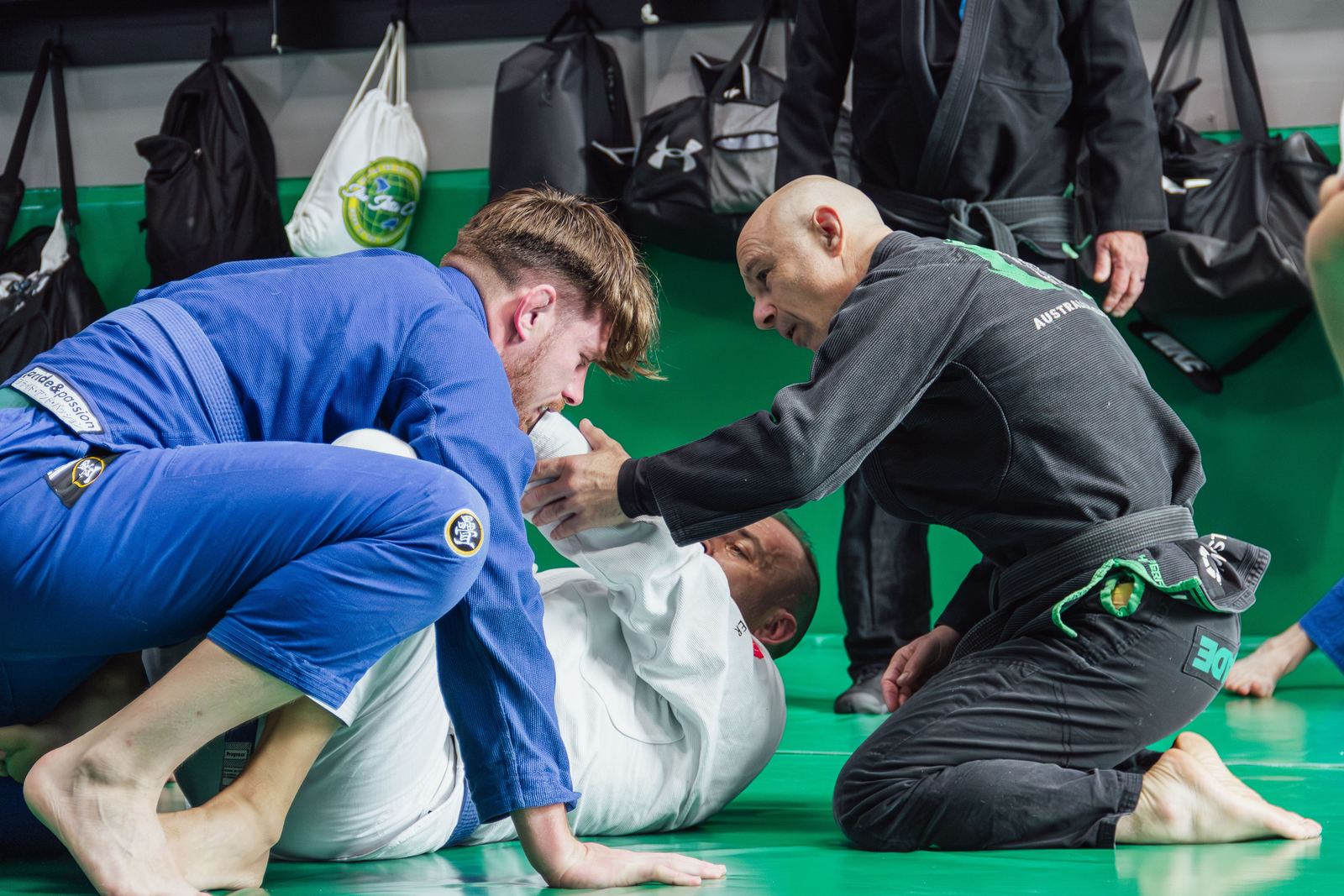 A coach helping a beginner during a White Belt class at Renegade