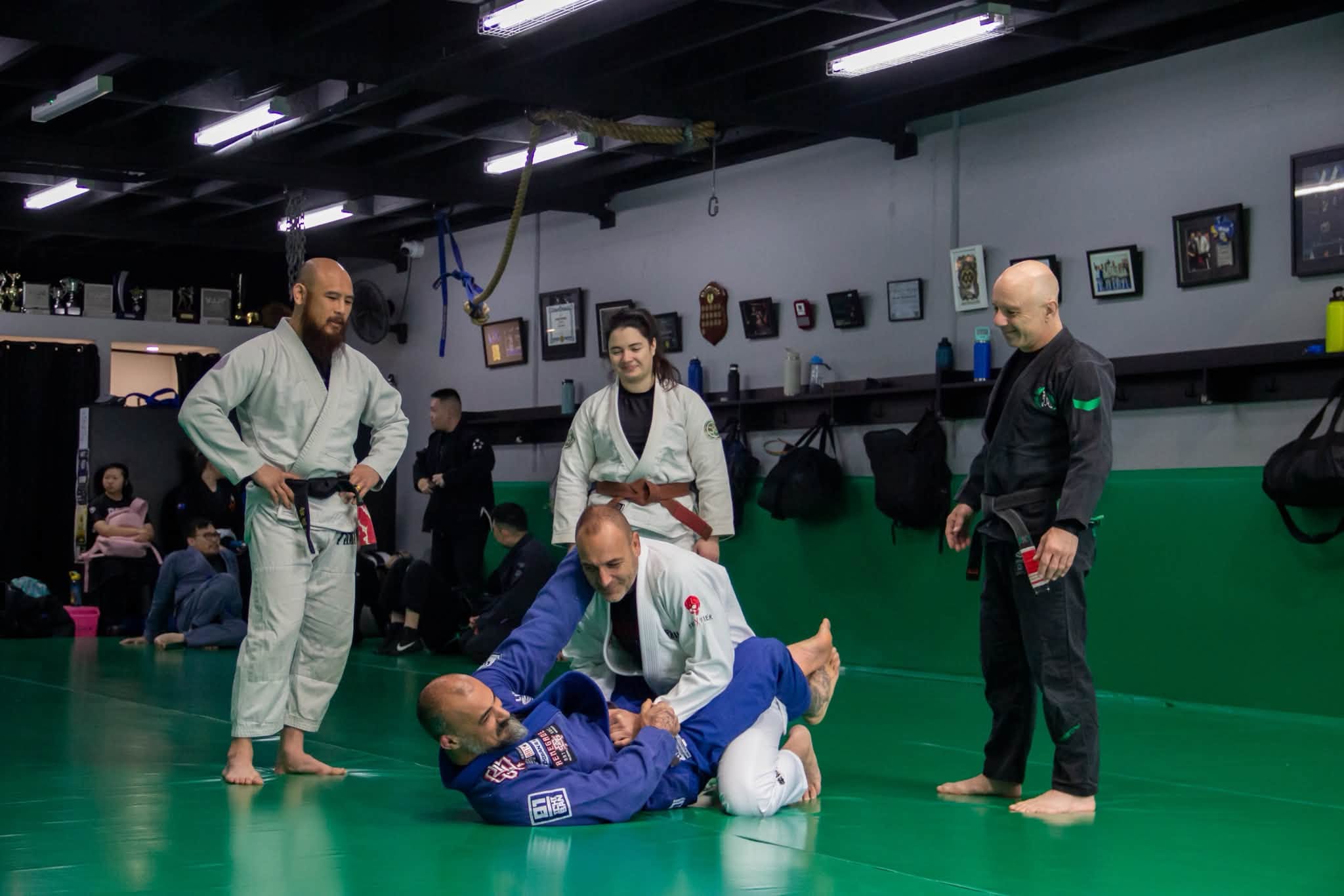 A Brazilian Jiu-Jitsu class at Renegade in Kensington: two students drilling on the mat while the coaches watch